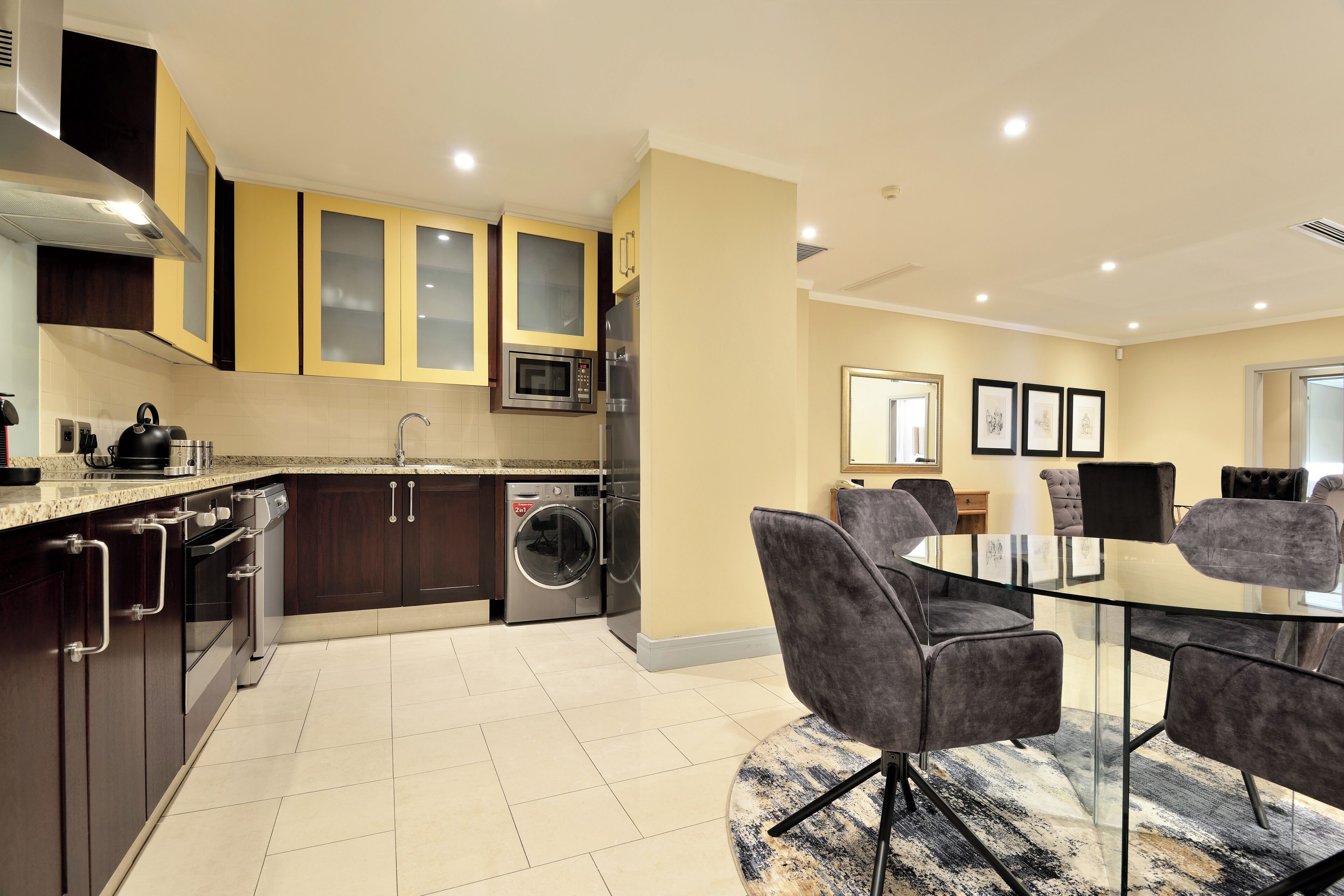 A modern kitchen with dark wooden cabinets, a built-in microwave, and a washing machine.