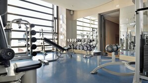 A gym with exercise equipment, large windows, and a blue floor. - The Raphael Penthouse Suites (Johannesburg)