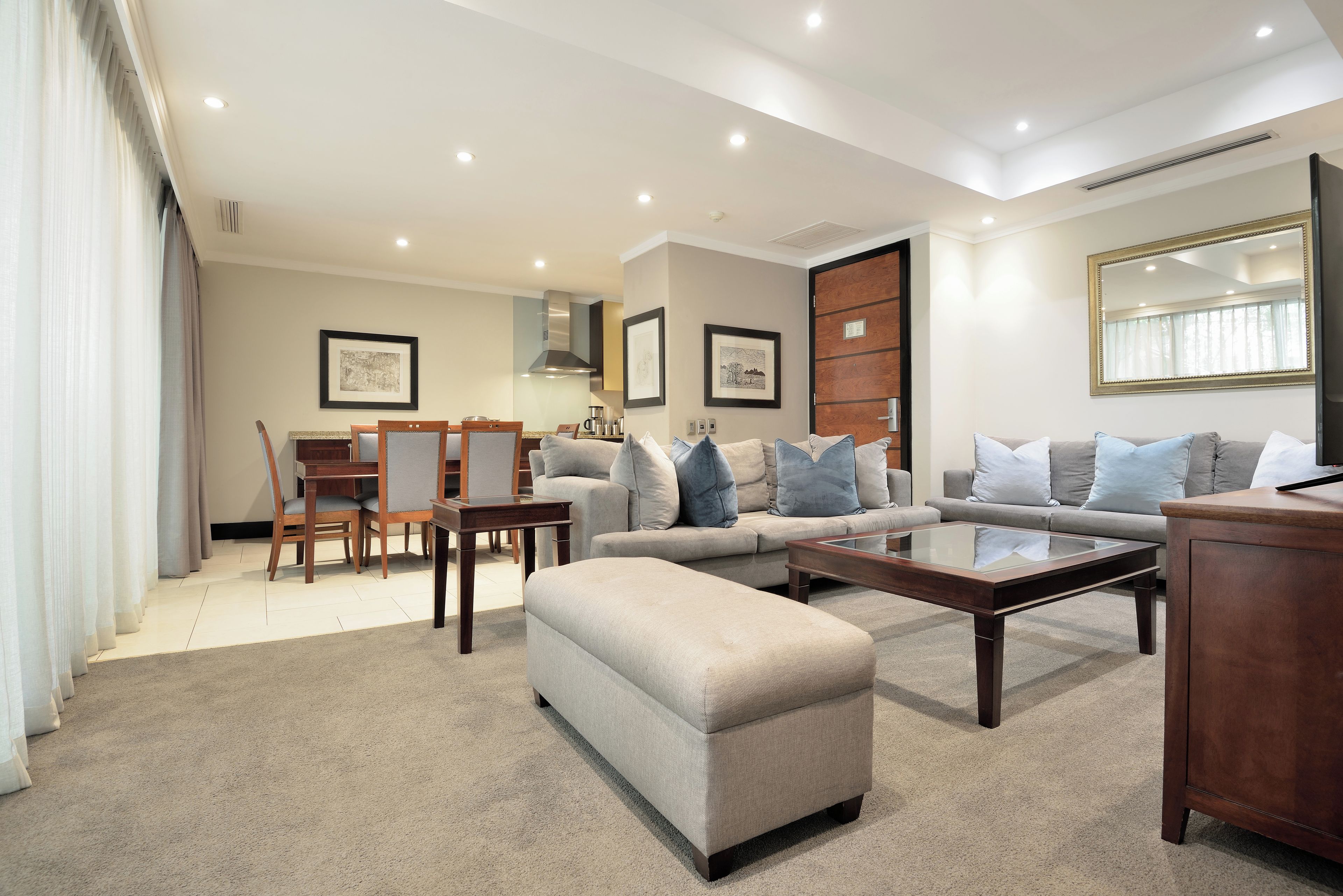 A modern living room with a sofa, ottoman, coffee table, and dining area.