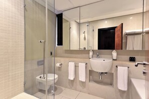 A modern bathroom with a glass shower enclosure, a toilet, a sink, and a bathtub. - The Raphael Penthouse Suites (Johannesburg)