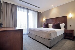 A hotel room with a large bed, a wooden desk, and two bedside lamps. - The Raphael Penthouse Suites (Johannesburg)