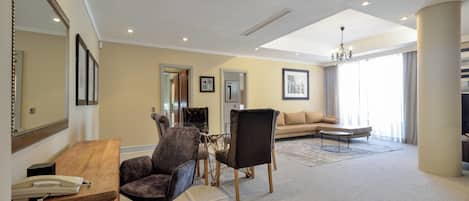 A spacious living room with a wooden desk, a sofa, and a chandelier.