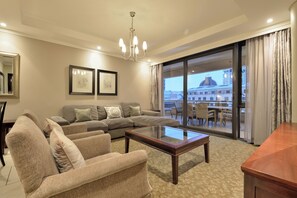 A living room with a sofa, chairs, a glass coffee table, and a view of a building through a large window. - The Raphael Penthouse Suites (Johannesburg)