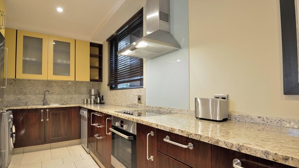 A modern kitchen with granite countertops, stainless steel appliances, and wooden cabinets. - The Raphael Penthouse Suites (Johannesburg)