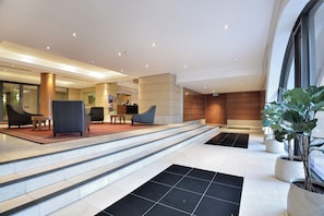 A modern lobby with a reception desk, seating area, and a staircase leading to upper floors. - The Raphael Penthouse Suites (Johannesburg)