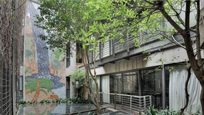 A modern building with a glass atrium, a mosaic wall, and a small garden area. - The Raphael Penthouse Suites (Johannesburg)