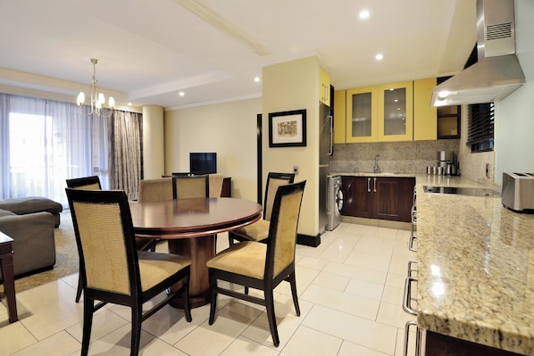 A modern hotel room with a dining area, kitchen, and living space. - The Raphael Penthouse Suites (Johannesburg)