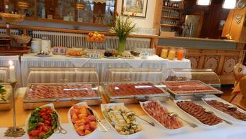 Un buffet proposant une variété de plats, notamment des viandes, des fromages et des fruits.