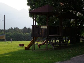 A playground with a slide and a wooden playhouse. - Hotel Landhof Simeter Gmbh (Spittal an der Drau)