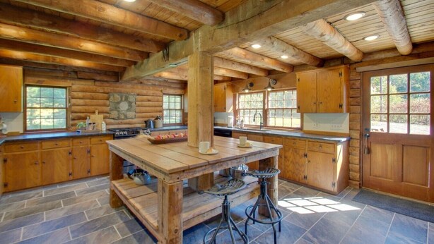 A rustic cabin-style kitchen with a large island, wooden cabinets, and stone accents.