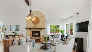 Ein Wohnzimmer mit Kamin, Sofa, Sessel und Fernseher.