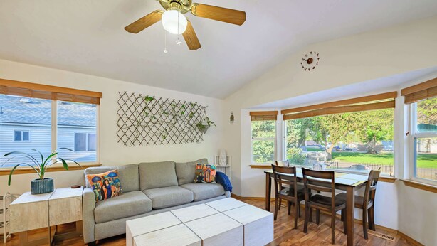 Un salon comprenant un canapé, une table à manger avec des chaises, un ventilateur de plafond et une fenêtre donnant sur l’extérieur.