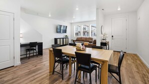 Een modern interieur met een eethoek, een bank, een televisie en een trap.