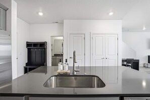 Eine moderne Küche mit einer großen Kochinsel, Spüle aus Edelstahl und einem eingebauten Schrank.