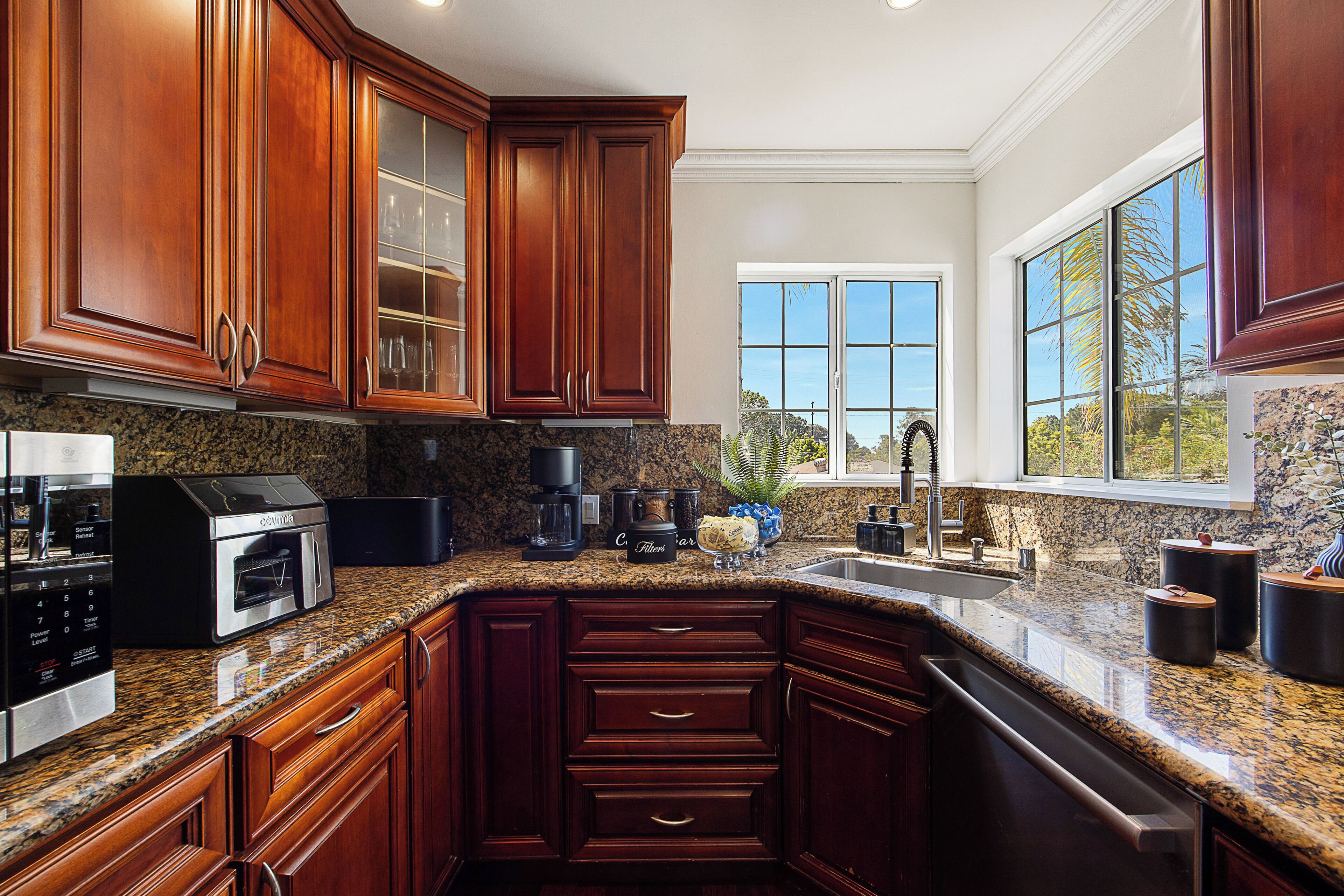 A kitchen with granite countertops, wooden cabinets, a built-in oven, and a large window.
