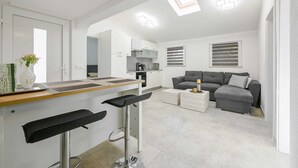 A modern kitchen with a bar area, a grey sofa, and a dining table. - Gasparevic Apartment 5 (Rovinj)