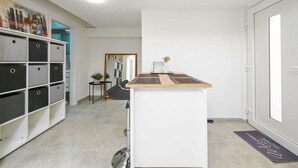 A clean, modern interior with a white storage unit, a small wooden table, and a mirror. - Gasparevic Apartment 5 (Rovinj)
