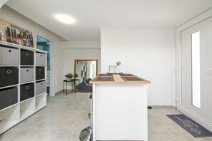 A clean, modern interior with a white storage unit, a small wooden table, and a mirror. - Gasparevic Apartment 5 (Rovinj)