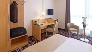 A hotel room with a bed, a desk, a chair, a TV, a coat rack, and a plant. - 2 Person Holiday Park Home in Dortmund (Dortmund)