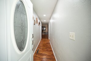 A hallway with a wooden floor, white walls, and a door with a glass panel. - Gorgeous 3 Bed 1.5 Bath House in Premium location (Springfield)