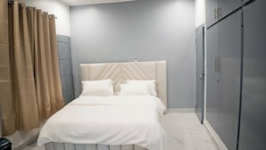 Ein Schlafzimmer mit Bett, Vorhängen, Kopfteil, Kleiderschrank und Mülleimer.