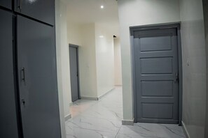 A hallway with a grey door, a white door, and a white tiled floor. - Appartement Chic Bastos - High Security, Air Conditioning, Wifi (Yaoundé)