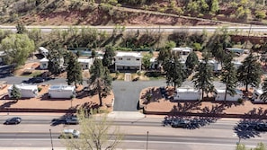Un terrain de camping avec des camping-cars, un bâtiment principal et une route où circulent des véhicules.