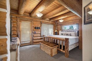 Ein Schlafzimmer in einer Blockhütte mit einem Holzbett, einer Bank und Holzbalken an der Decke.