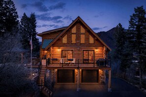Eine Blockhütte mit Balkon, Treppe und Garage.