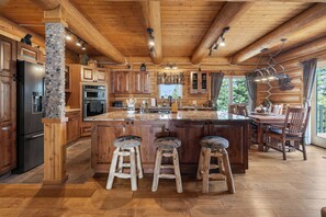 Ein Holzblockhaus-Interieur mit Küche, Essbereich und Barhocker.