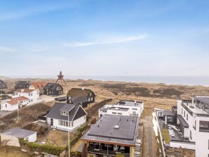 Ein Küstenwohngebiet mit modernen Häusern, einer Windmühle und Blick auf das Meer.