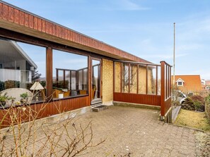 Ein modernes Gebäude mit großen Fenstern, einer Holzfassade und einem Kieshof.