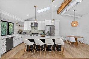 A modern kitchen with white cabinetry, stainless steel appliances, a central island with bar stools, and pendant lighting. - Arcadia 5BR Oasis, Pool, Putting Green & Sleeps 12 (Phoenix)