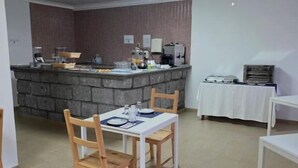 A dining area with a stone counter, a table set for two, and a small white table in the corner.
