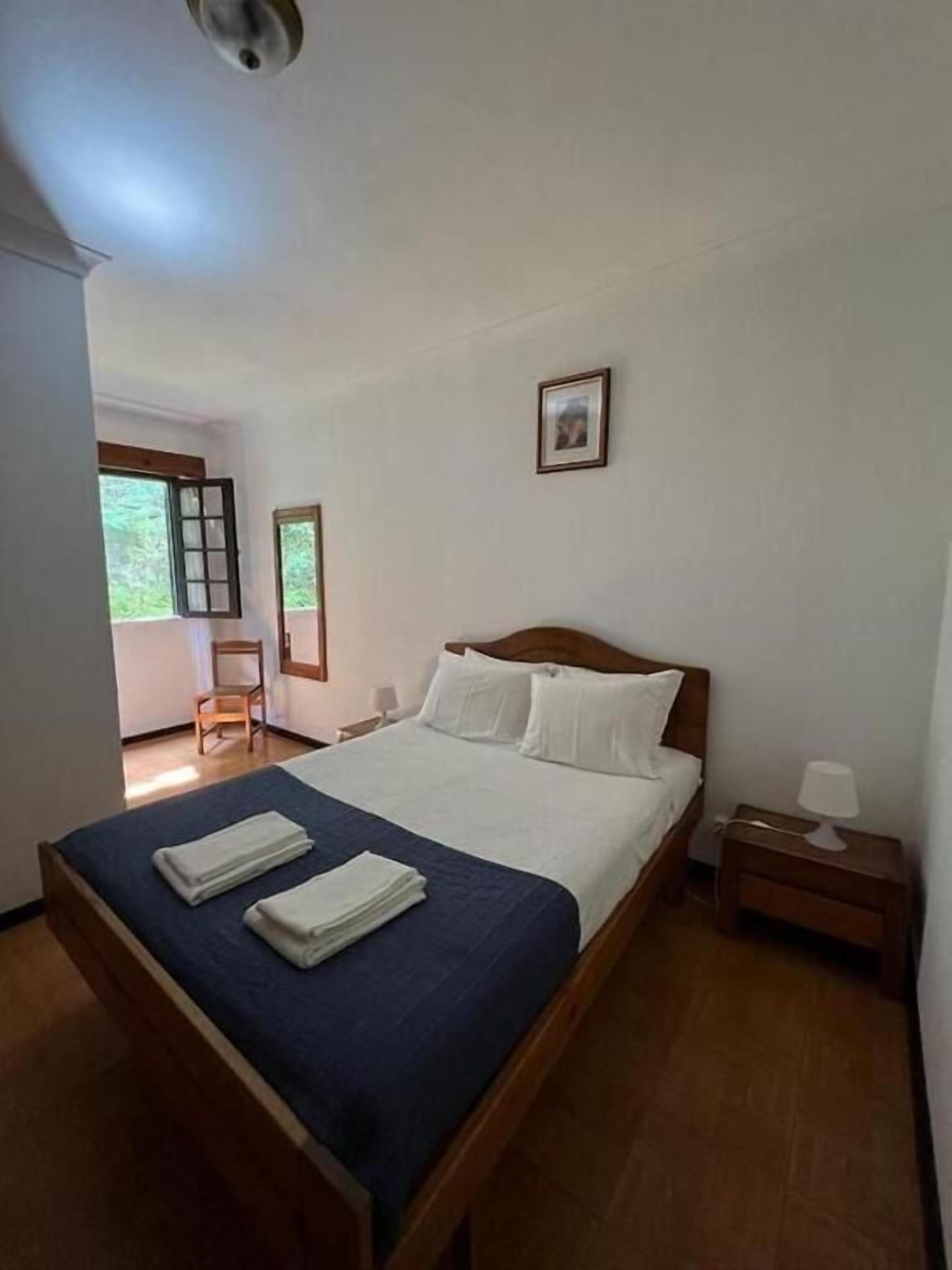 Une chambre à coucher avec un lit, une chaise, une table de chevet et un tableau au mur.