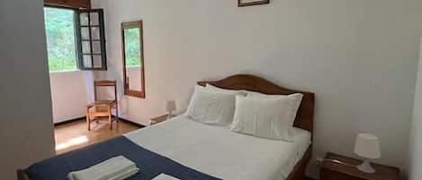 A bedroom with a bed, a chair, a nightstand, and a picture on the wall.
