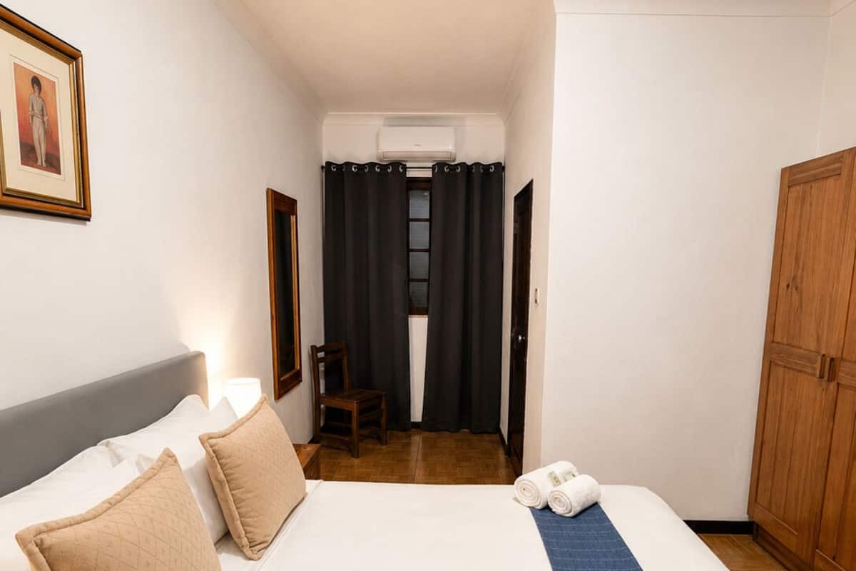 Una habitación de hotel con una cama grande, una silla, un armario y un cuadro en la pared.