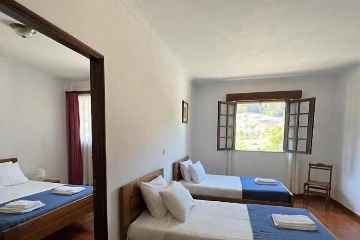 Una habitación con dos camas, un ventanal y una puerta.