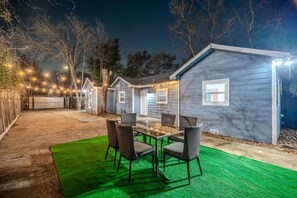 A house with a patio area featuring a glass-top table and wicker chairs. - Cozy 6BR Oasis, Fire Pit, Sleeps 13,Near DT (Houston)