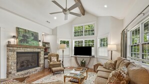 A living room with a fireplace, a television, a sofa, and a coffee table. - Wooded Highlands Cottage - Patios & Fireplace (Highlands)