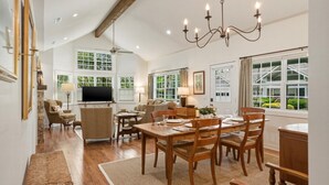 A spacious living room with a dining area, large windows, and a chandelier. - Wooded Highlands Cottage - Patios & Fireplace (Highlands)
