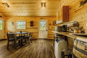 Een houten chalet interieur met een eettafel, stoelen, een keukenhoek met een fornuis en een koelkast.