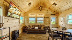 Ein Holzblockhaus-Interieur mit einer Couch, einem Esstisch und einem Schild für Serenity Smoked.