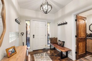 A hallway with a bench, a chandelier, and a door with a wooden finish. - StayIncline at Village at Incline (VAI49) (Incline Village)