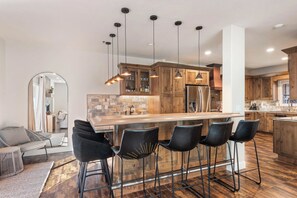 A modern kitchen with a central island, bar stools, wooden cabinets, and pendant lighting. - StayIncline at Village at Incline (VAI49) (Incline Village)