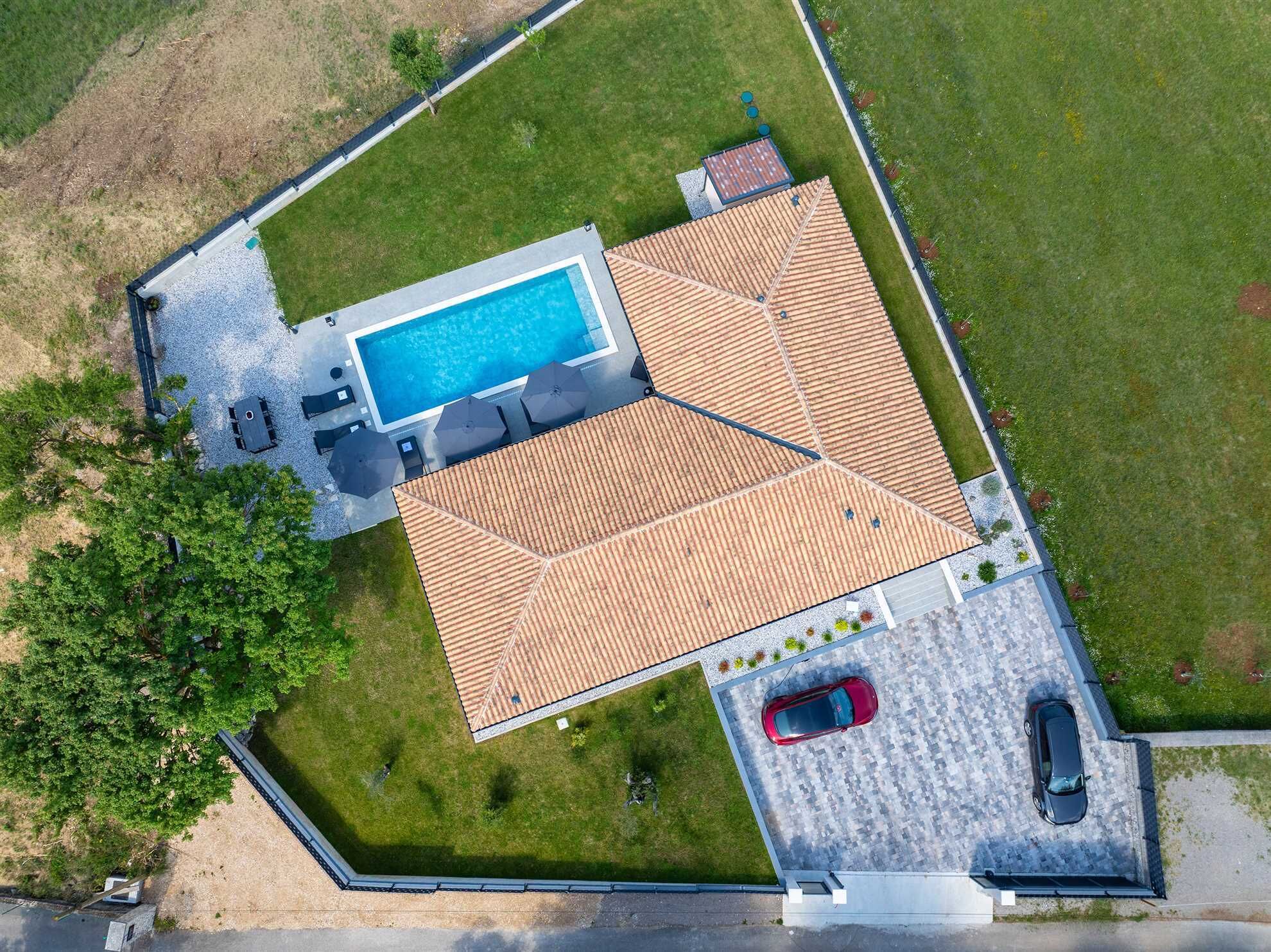 Vista aérea de una propiedad con piscina, terraza techada y zona de estacionamiento.