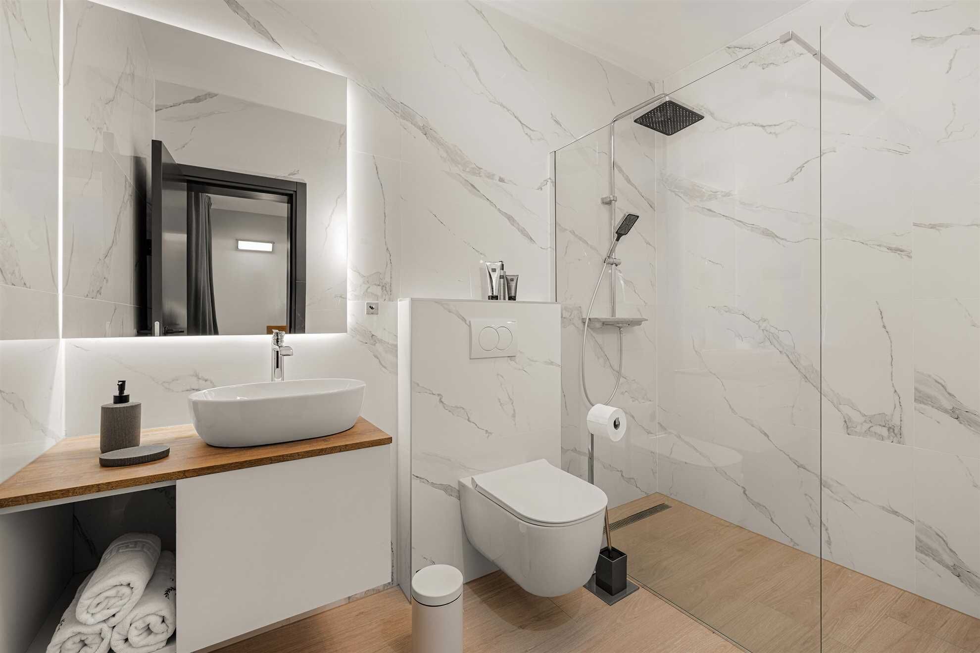 A modern bathroom with a freestanding sink, a toilet, and a shower enclosure.