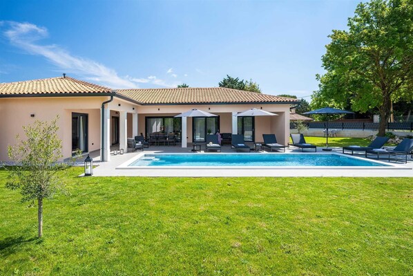 Ein Haus mit Swimmingpool, Sitzgelegenheit im Freien und einem gepflegten Rasen.