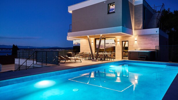 A modern two-story building with a rooftop pool area, outdoor seating, and a view of the mountains. - Beautiful home in Zdrelac with sauna (Zdrelac)