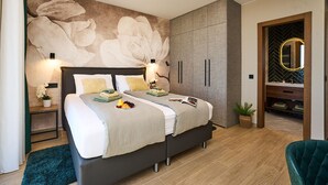 A modern bedroom with a large bed, bedside lamps, a wardrobe, and a bathroom visible through an open door. - Beautiful home in Zdrelac with sauna (Zdrelac)